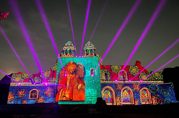 A colourful, patterned image shining on the side of an Indian temple