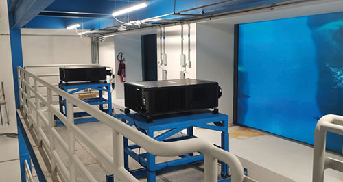 Two Crimson WU31 projectors facing acrylic windows with blue water on the other side
