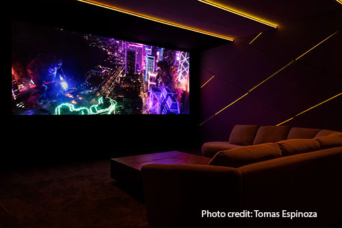 A darkened room with a sectional couch in front of a projection screen.