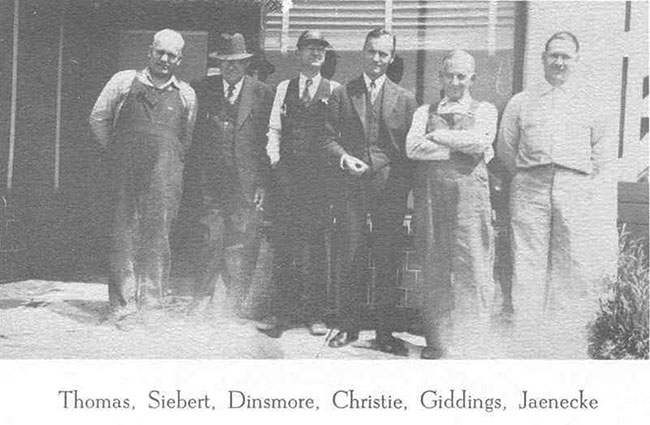 Six men standing in front of a building.