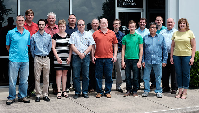 Group of people posed in front of the glass façade of a commercial building.