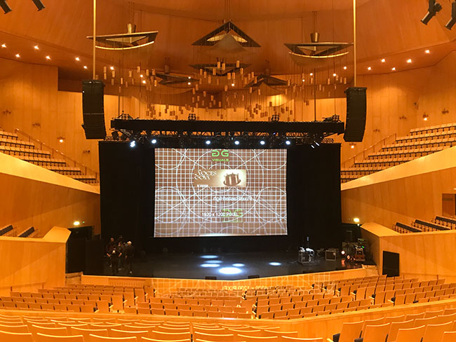 A projection screen shows a grid pattern in an empty theatre.
