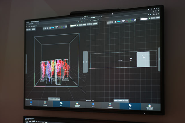 A wall-mounted display shows computer-generated outlines of people.