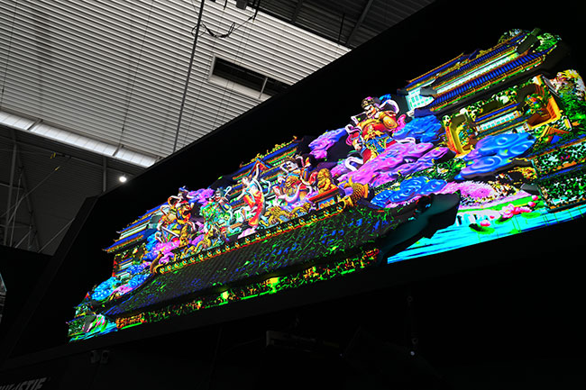A large 3D temple-inspired art piece is projection mapped with vibrant colors.