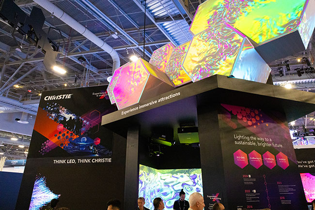 A trade show booth with bright graphics and projection mapped hexagons.