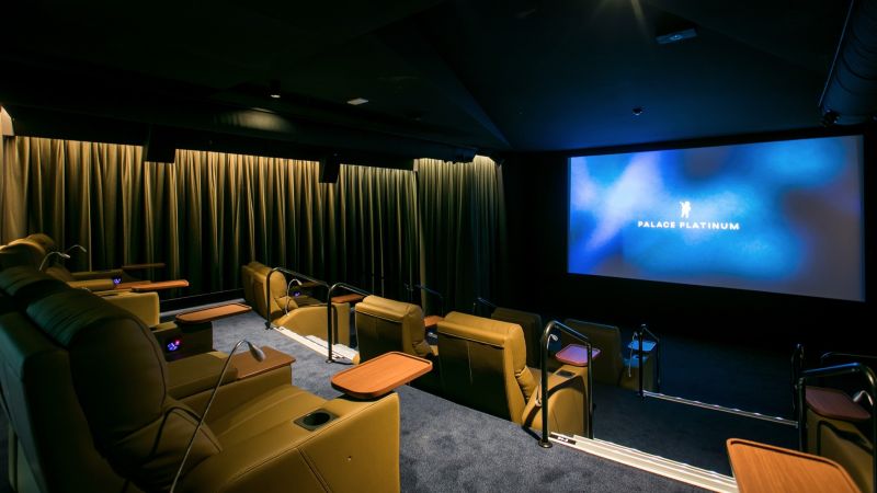 A dark movie theatre with striking green lighting and accents.